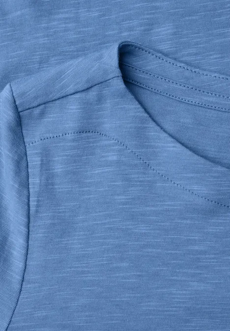 Nahaufnahme eines ärmellosen, hellblauen Shirts mit feiner Slub-Struktur.