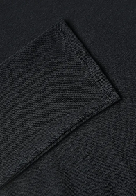 Nahaufnahme eines schwarzen Baumwollshirts, bei dem ein Ärmel angedeutet gefaltet ist.