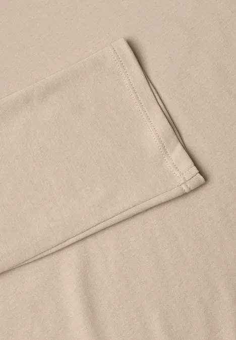 Beige Stoff oder T-Shirt mit sichtbarer Naht, leicht gefaltet auf glattem Untergrund