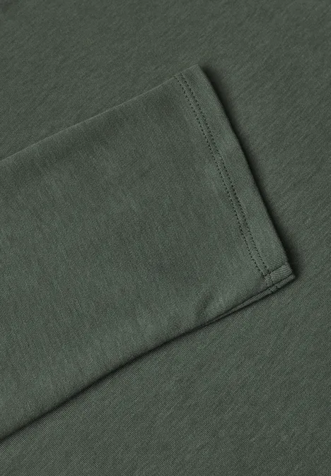Close-up van de zoom van een donkergroene katoenen T-shirtmouw met nette stiknaad.