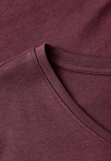 Nahaufnahme eines burgunderroten V-Hals-T-Shirts aus weichem Stoff.