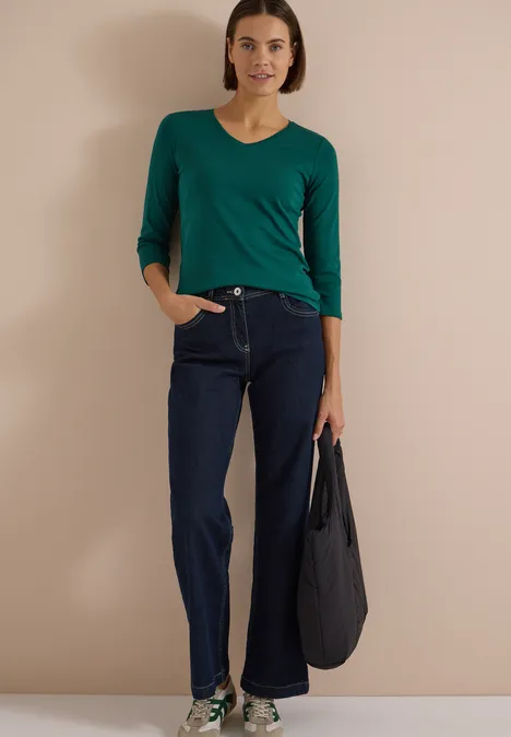 3/4-Arm Shirt in Unifarbe mit V-Neck dark fir green Frau trägt grünes V-Shirt mit 3/4-Ärmeln, dunkle Jeans und hält eine schwarze Tasche.