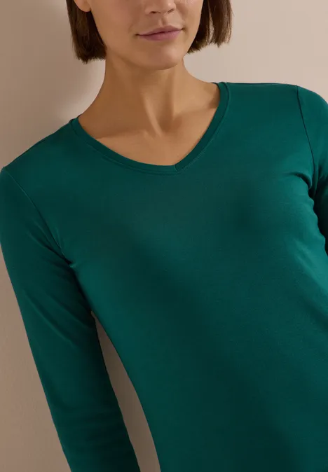3/4-Arm Shirt in Unifarbe mit V-Neck dark fir green Frau in grünem V-Ausschnitt-Langarmshirt, Oberkörperaufnahme.