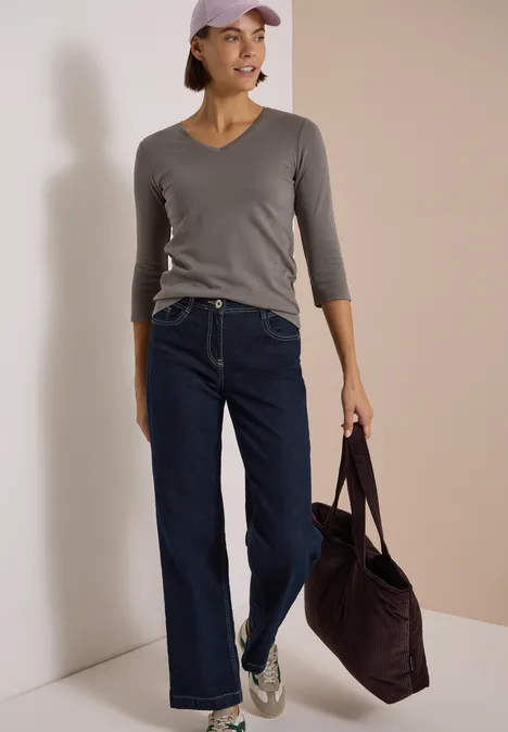 3/4-Arm Shirt in Unifarbe mit V-Neck storm grey Eine Frau trägt ein graues Langarmshirt, dunkelblaue Jeans, Sneaker und eine Tasche.