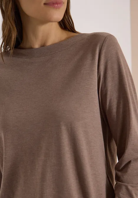 Persoon draagt een eenvoudig bruin shirt met lange mouwen, zijaanzicht.