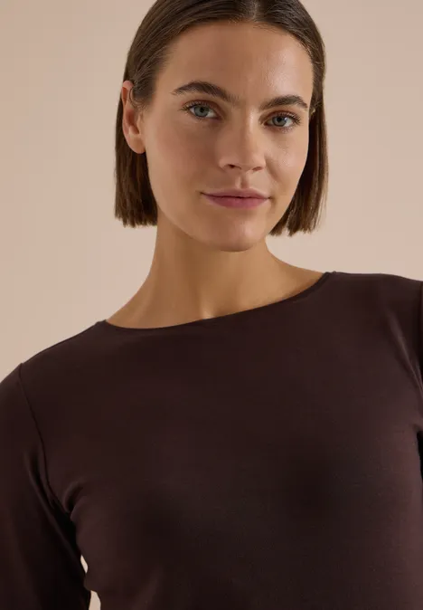 Langarm Shirt mit U-Boot-Ausschnitt truffle brown Eine Frau mit kurzem dunklem Bob trägt ein schokoladenbraunes Oberteil und schaut freundlich in die Kamera.