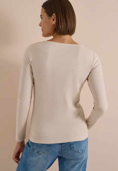 Langarm Shirt mit U-Boot-Ausschnitt cashmere beige Frau von hinten in hellbeigem Langarmshirt und blauen Jeans vor hellem Hintergrund.