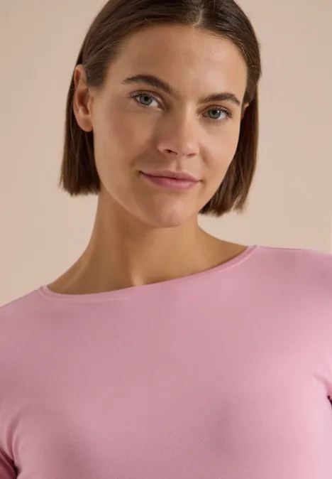 Langarm Shirt mit U-Boot-Ausschnitt mellow rose Junge Frau mit kurzen braunen Haaren und rosa Oberteil vor hellem, neutralem Hintergrund, leichtes Lächeln.