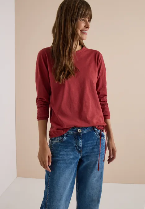 Langarm Shirt mit Rundhals und Tunnelzug russet red Frau mit rotem Langarmshirt und blauen Jeans vor hellem Hintergrund