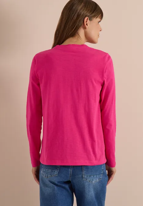 Langarm Shirt mit Rundhals und Tunnelzug pink flash Eine Frau von hinten in rosa Langarmshirt und blauen Jeans vor einfarbigem Hintergrund.