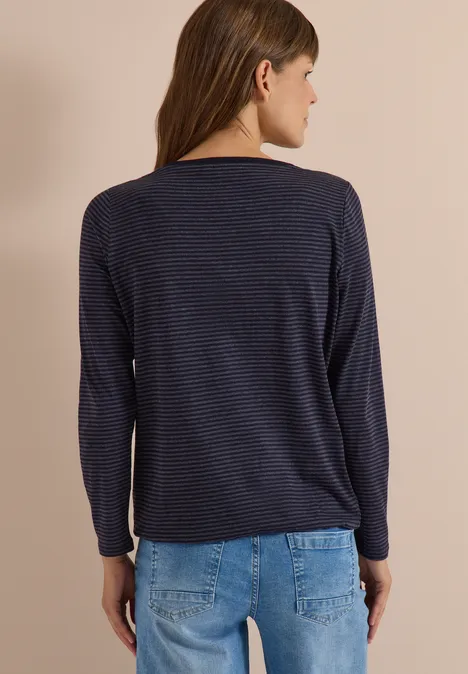 Femme vue de dos portant un haut à manches longues bleu foncé à fines rayures et un jean bleu clair.