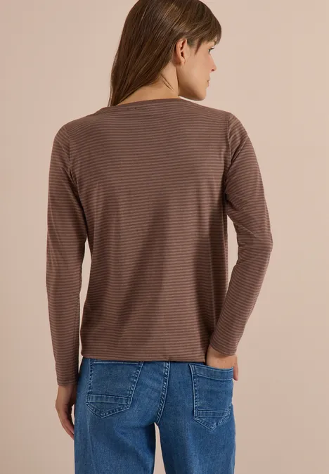 Frau von hinten trägt braunes, gestreiftes Langarmshirt und blaue Jeans.