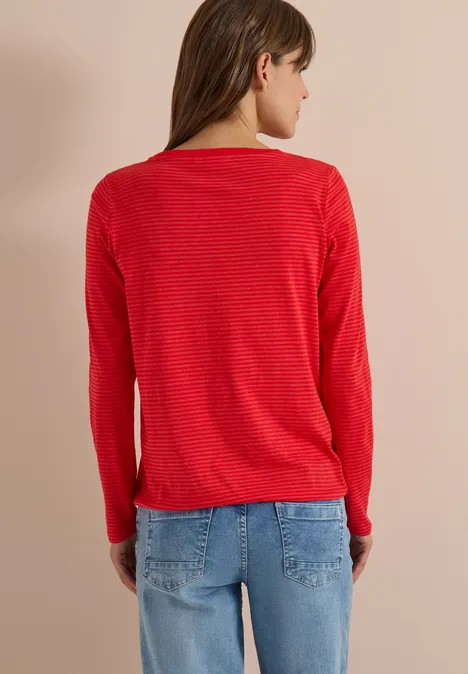 Une femme de dos portant un pull rouge et un jean bleu