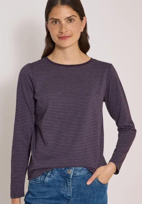 Langarm Shirt mit Boat Neck und Streifen lilac shadow Frau trägt dunkelblau-weiß gestreiftes Longsleeve und Jeans vor hellem Hintergrund.