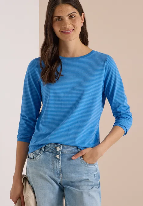 Langarm Shirt mit Boat Neck und Streifen north blue Frau trägt blaues Langarmshirt und helle Jeans, lächelt und hat die Hand in der Tasche.