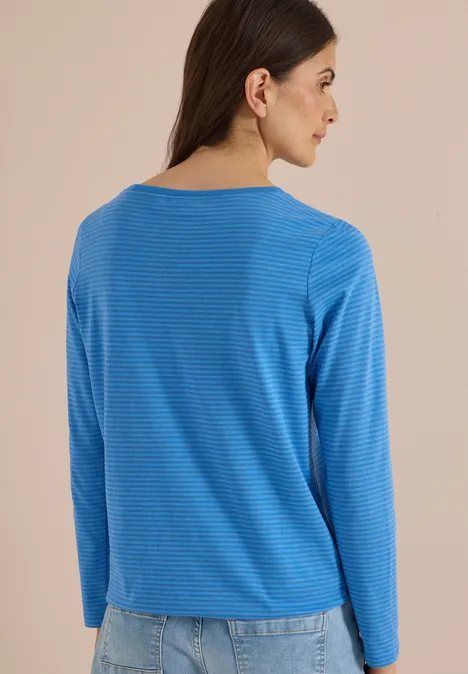 Langarm Shirt mit Boat Neck und Streifen north blue Frau von hinten in blau-weiß gestreiftem Langarmshirt und Jeans vor beigem Hintergrund.