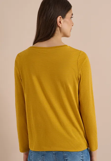 Langarm Shirt mit Boat Neck und Streifen golden honey Frau von hinten in senfgelbem, langärmligem Shirt und blauer Jeans vor beigem Hintergrund.
