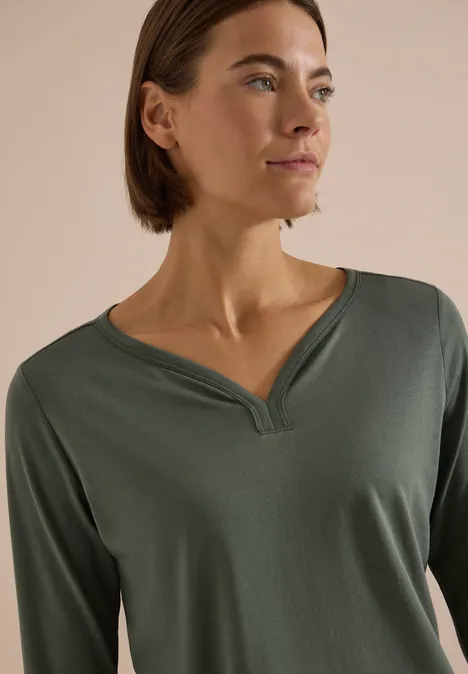Shirt mit Split Neck im Tunika-Look dried olive green Frau in khakifarbenem Langarmshirt mit modernem Schlitzkragen, schaut seitlich.