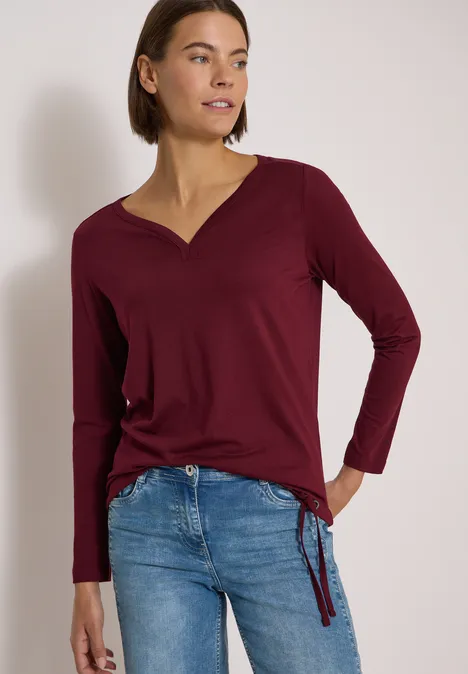 Shirt mit Split Neck im Tunika-Look red wine Frau in bordeauxfarbenem Langarmshirt und blauen Jeans mit seitlicher Schleife.