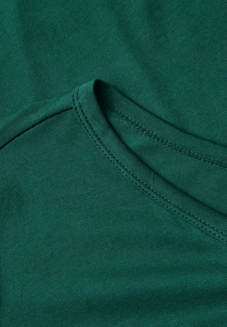 Close-up van de halslijn van een groen T-shirt met zichtbare naad