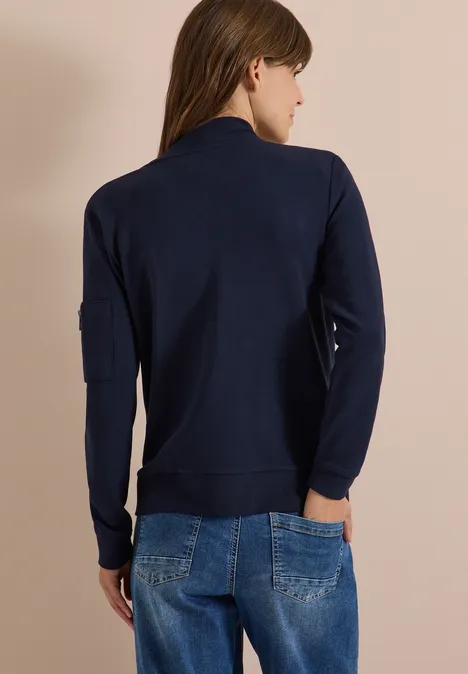 Ottoman Blouson in Unifarbe urban dark blue Frau von hinten in dunkelblauer Sweatjacke und Jeans vor beiger Wand.