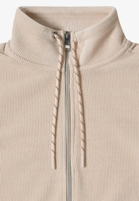 Beige, gerippter Pullover mit hohem Kragen, durchgehendem Reißverschluss und Kordelzügen an der Halsöffnung.