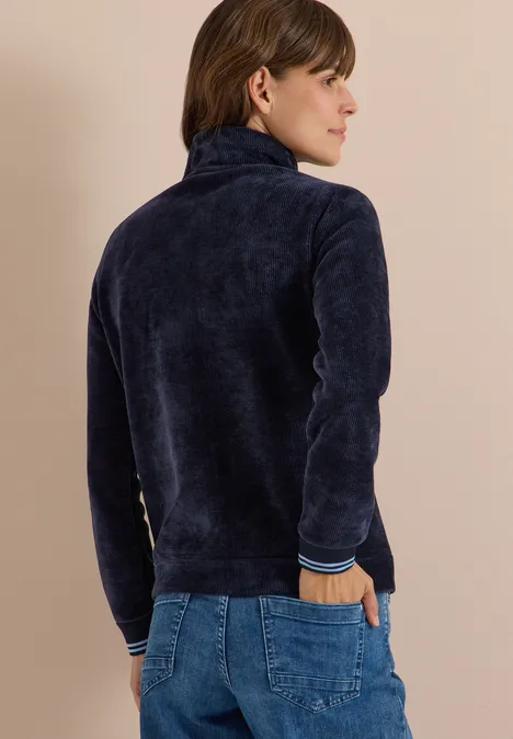 Frau trägt dunkelblaue, flauschige Fleecejacke mit Stehkragen und Jeans, Rückenansicht