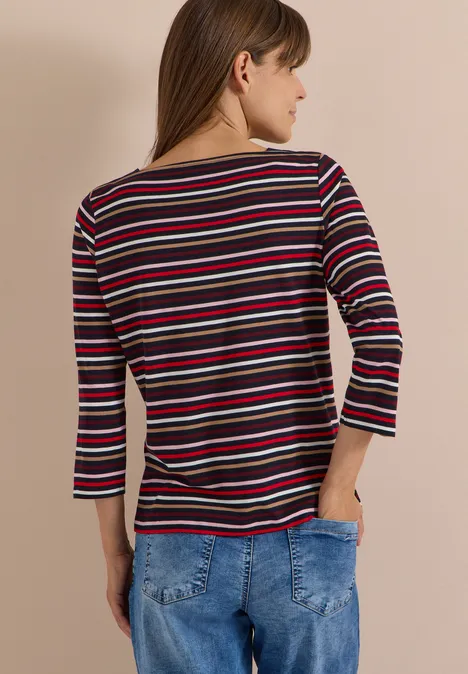 Femme de dos portant un haut à rayures multicolores et un jean bleu.
