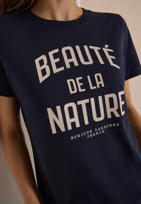 Femme portant un t-shirt bleu marine avec inscription blanche "Beauté de la Nature".