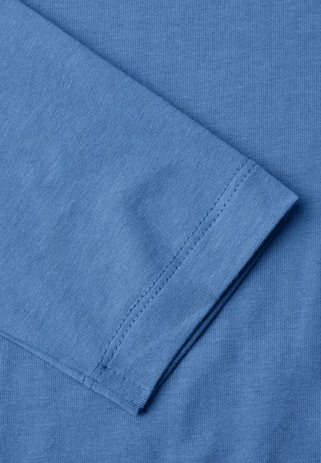 Nahaufnahme eines blauen T-Shirt-Ärmels mit feiner Naht und gefaltetem Stoff.