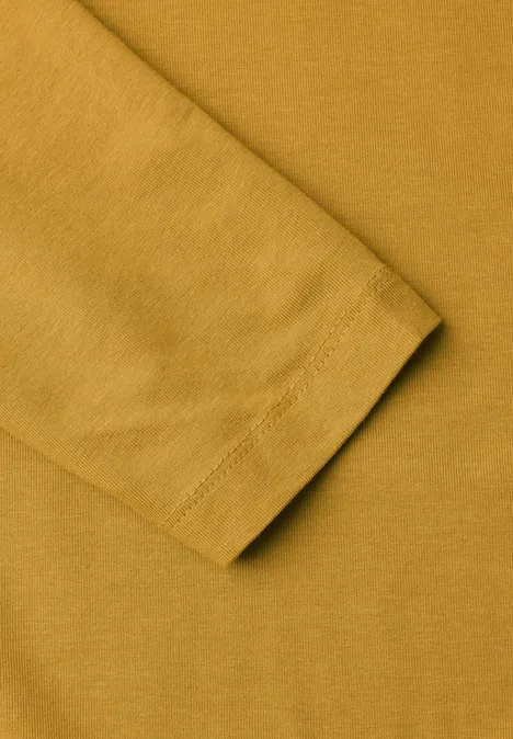 Langarm Shirt in Unifarbe mit Turtle Neck golden honey Nahaufnahme eines Ärmels eines senfgelben T-Shirts aus Baumwolle.