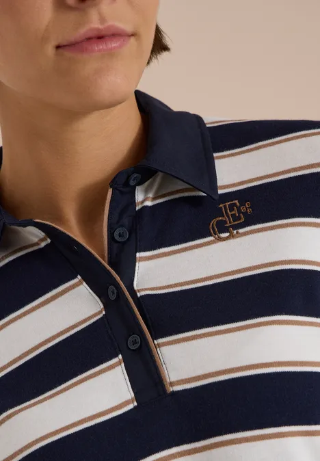 Personne porte un polo rayé bleu marine, blanc et beige avec un logo sur la poitrine.