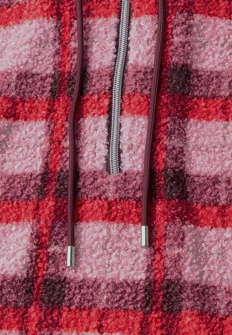 Nahaufnahme eines flauschigen, rot-rosa karierten Fleece-Hoodies mit Kordelzug.