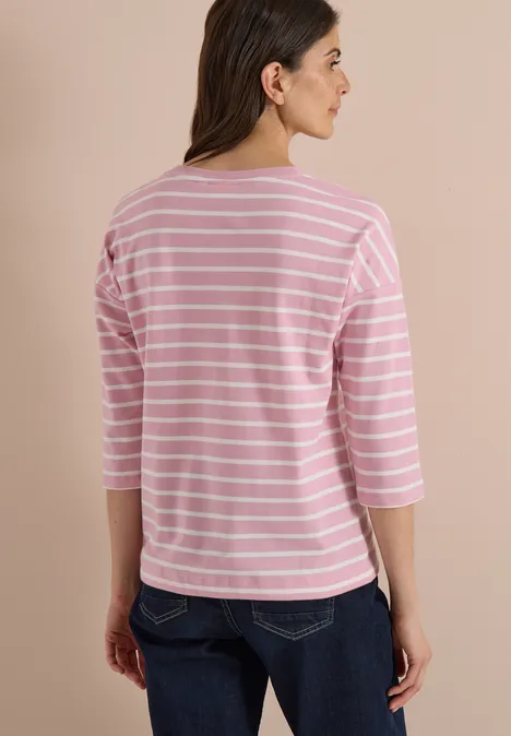 Frau von hinten in rosa-weiß gestreiftem 3/4-Arm-Shirt und Jeans.