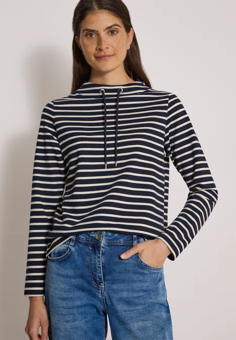 Langarm Shirt mit Funnel Neck und Streifen urban dark blue Frau mit blau-weiß gestreiftem Shirt und Jeans vor hellem Hintergrund.