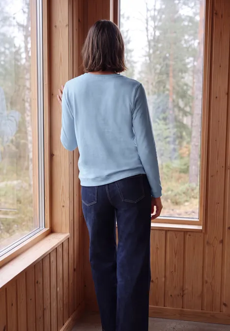 Langarm Shirt mit Tunnelzug am Saum cosmopolitan blue Eine Person steht in einem Holzraum und blickt durch große Fenster auf einen Wald.