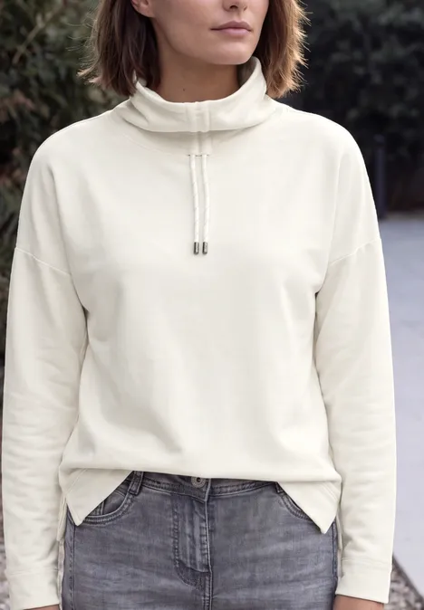 Shirt met lange mouwen, col en trekkoord vanilla white Vrouw draagt witte coltrui met koord en een grijze spijkerbroek, borstbeeld buiten gefotografeerd.
