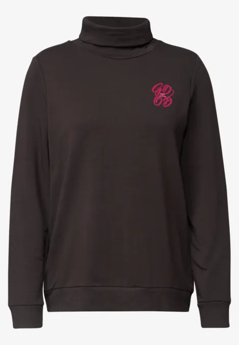 Zwarte coltrui met klein roze logo op de borst.