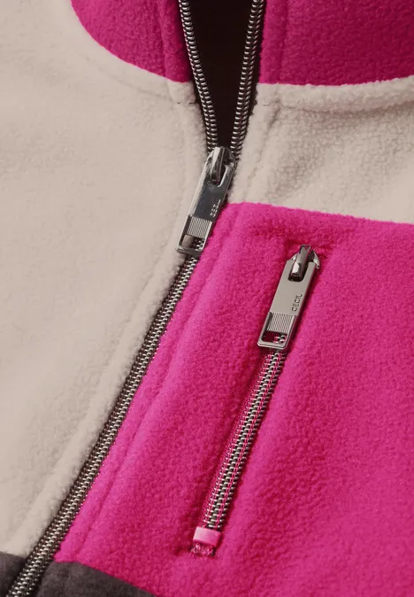 Nahaufnahme einer pink-beigen Fleecjacke mit zwei silbernen Reißverschlüssen