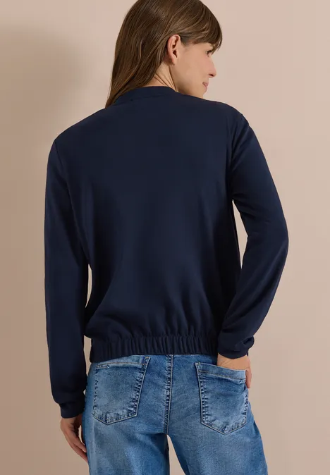 Blouson mit Strukturmix und Elastiksaum urban dark blue Rückansicht einer Frau in dunklem Langarmshirt mit gerafftem Saum und blauer Jeans, Hände in den Taschen.