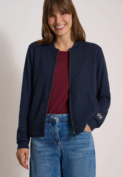 Blouson mit Strukturmix und Elastiksaum urban dark blue Junge Frau trägt blaue Jacke, bordeauxfarbenes Shirt und Jeans und lächelt.