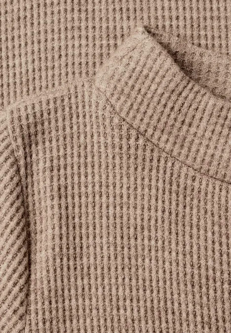 Pull en maille beige à col roulé et motif épais.