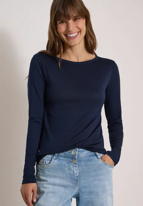 Langarm Shirt in Unifarbe mit Boat Neck urban dark blue Eine Frau mit brünetten Haaren lächelt, sie trägt ein dunkelblaues Langarmshirt und Jeans.