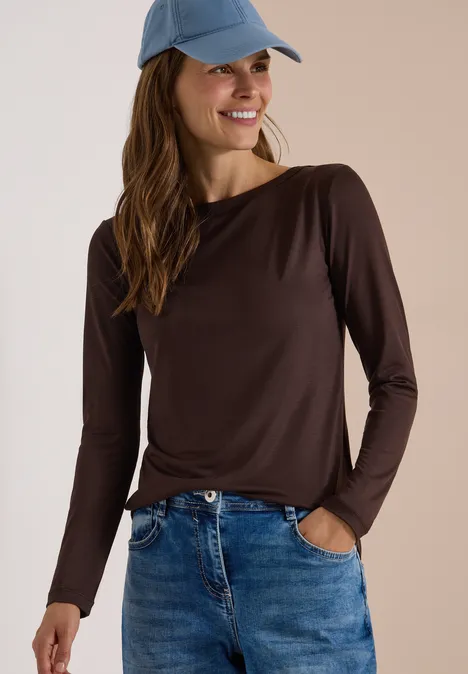 Langarm Shirt in Unifarbe mit Boat Neck truffle brown Junge Frau in braunem Langarmshirt, Jeans und Cap lächelt mit Händen in den Hosentaschen.