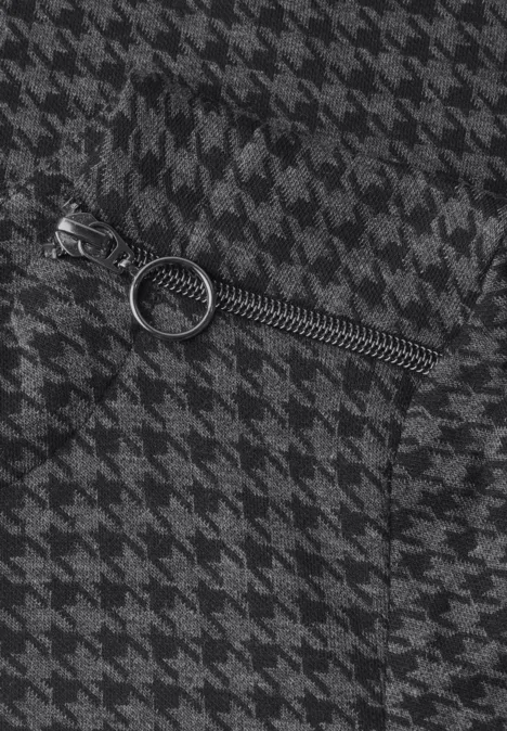 Nahaufnahme eines Reißverschlusses mit rundem Zipper auf schwarz-weißem Hahnentrittmuster.