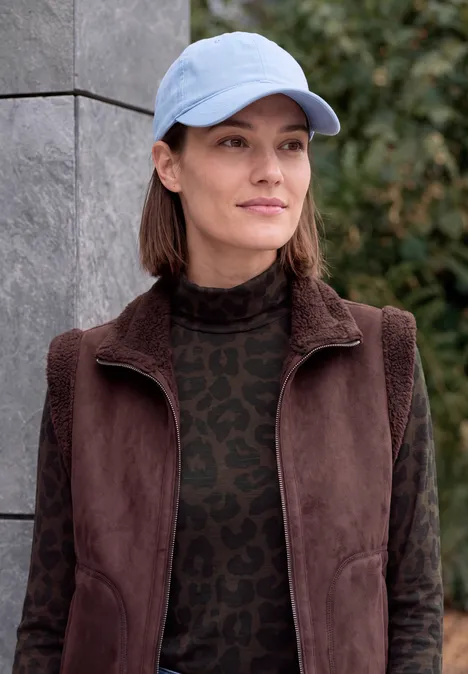 Shirt met lange mouwen, col en luipaardprint truffle brown Eine Frau mit blauer Baseballkappe und brauner Jacke steht draußen vor einer Mauer.