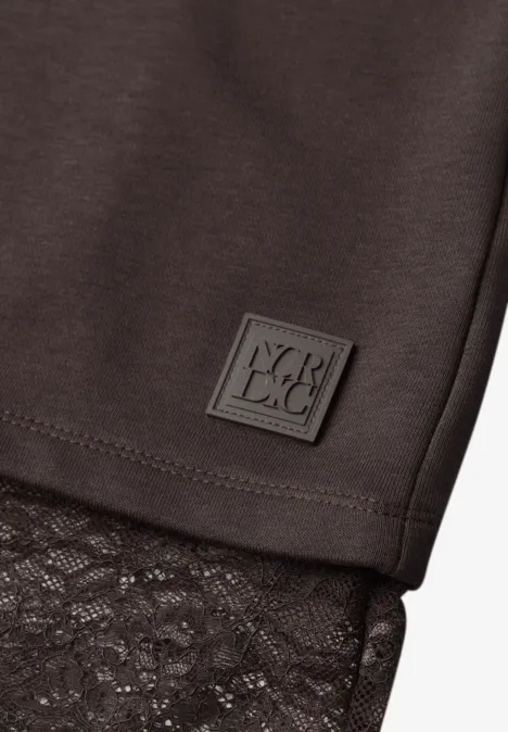 Shirt met lange mouwen, ronde hals en kanten rand truffle brown Close-up van een zwart kledingstuk met kanten zoom en klein vierkant logopatch.