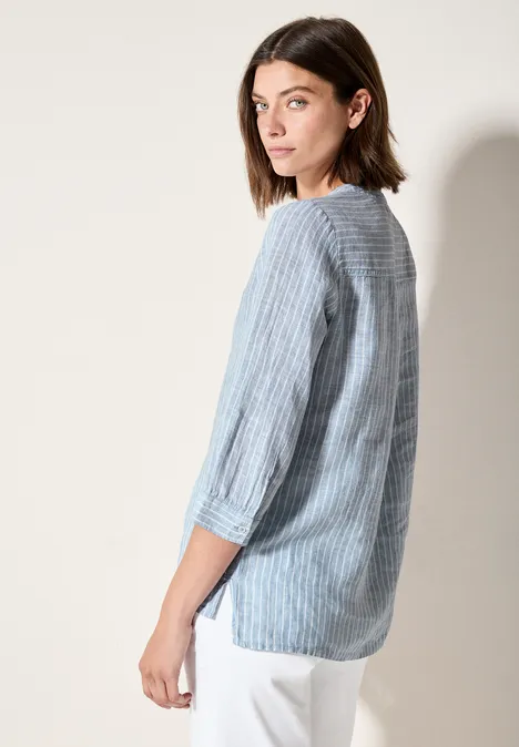 Vrouw met blauw-wit gestreepte blouse kijkt over haar schouder.