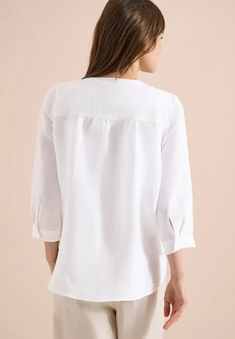 Frau von hinten in locker sitzender weißer Bluse mit 3/4-Ärmeln.
