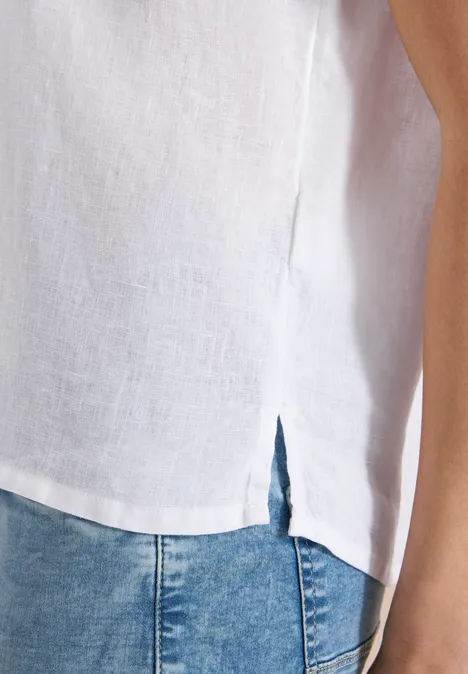 Weiße Leinenbluse mit seitlichem Schlitz, kombiniert mit blauen Jeans.